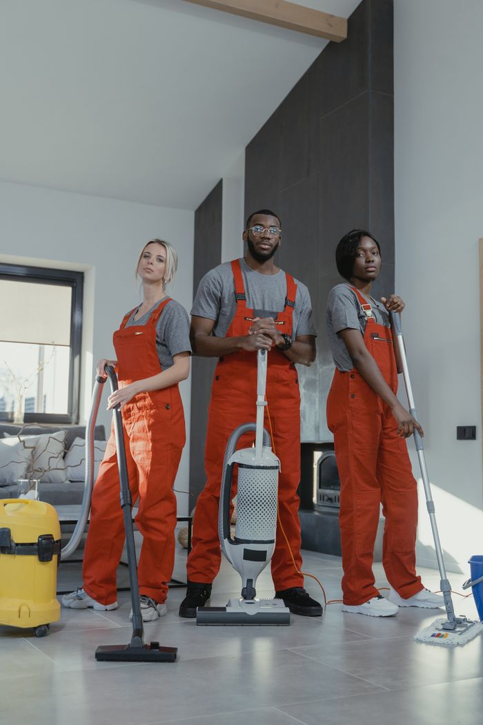 team-01 Three cleaners in uniform with equipment in a modern home interior, showcasing teamwork and professionalism.